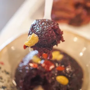 a person holding a spoon with a chocolate dessert on it