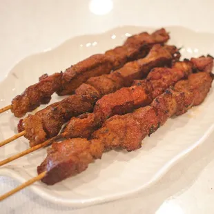 skewered meat on a white plate