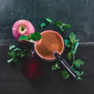 a smoothie in a glass with a straw and an apple