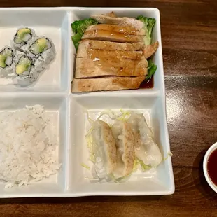 Bento box of California roll, hibachi chicken, rice, and pork gyoza