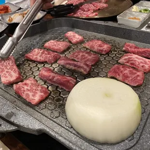 a person cutting meat on a grill