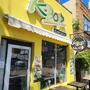 a yellow building with tables and chairs outside