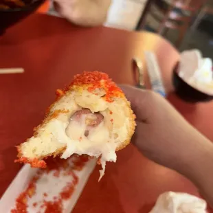 a hand holding a piece of pizza