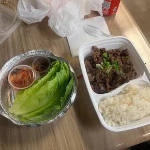 a tray of rice, lettuce, and beef