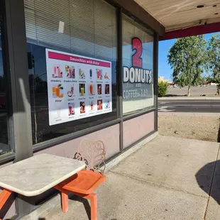 a table and chairs in front of a donut shop