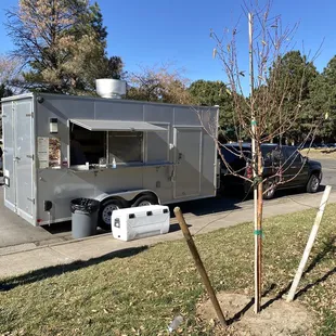 a food truck parked next to a tree