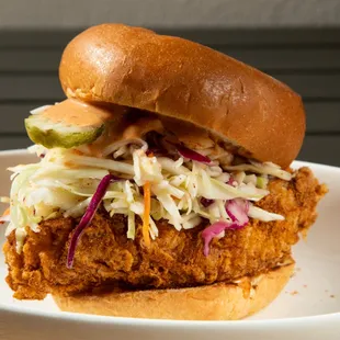 a fried chicken sandwich with coleslaw and pickles