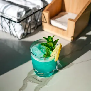 a blue drink with a lemon wedge