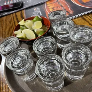 a plate of shot glasses and a bowl of limes