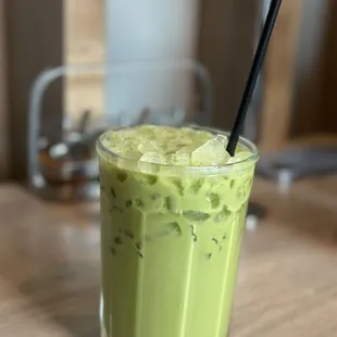 a glass of green tea with a straw