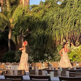 two hawaiian dancers performing in a courtyard setting