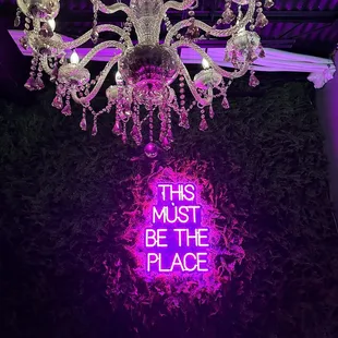 Entrance has a neon sign at the desk and pretty chandelier