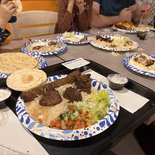 a group of people sitting at a table with plates of food