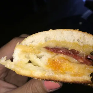 a hand holding a half eaten sandwich