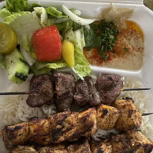 Three skewer plate. Two chicken and one steak with rice and salad.
