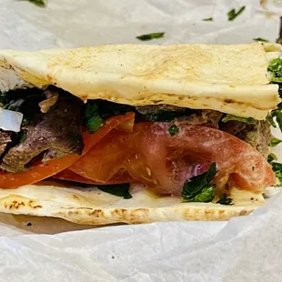 an open pita with meat and vegetables