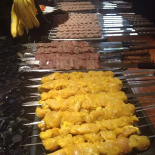 a variety of meats being cooked on skewers