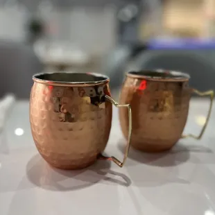 two copper mugs on a table