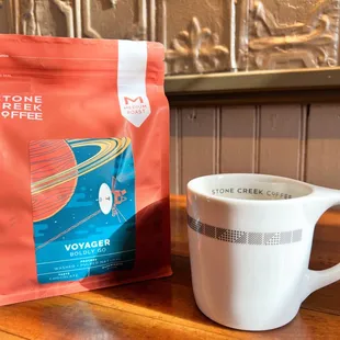 a cup of coffee next to a bag of coffee