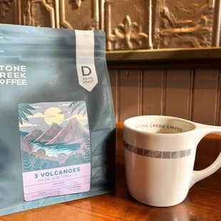 a cup of coffee next to a bag of coffee