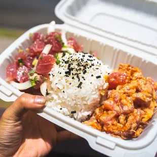 a hand holding a take out container of food