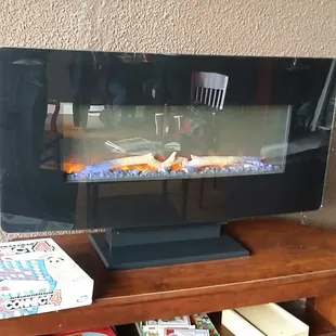 A cozy electric fireplace. There are cushioned chairs sat by a nice little coffee table in front of it, too.