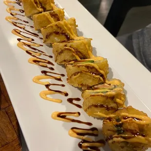 a long plate of food with sauce drizzled on it