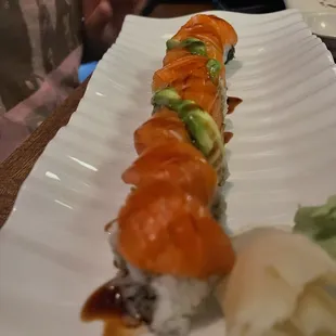 a sushi roll with salmon, avocado, and sauce