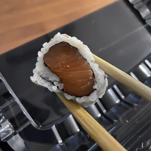 chopsticks holding a piece of sushi