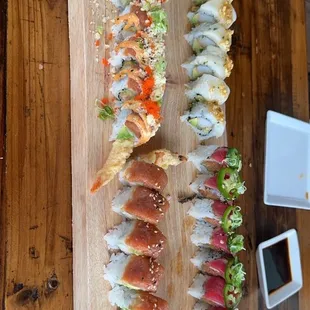 a wooden board with a variety of sushi on it