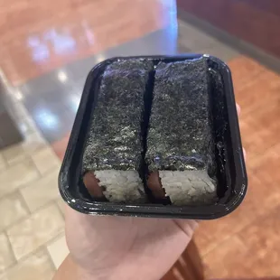 a hand holding a piece of sushi