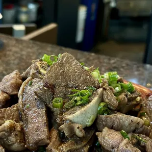 a plate of beef and green onions