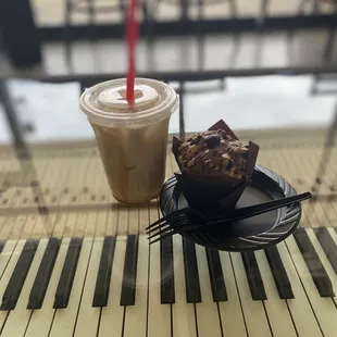 a cup of coffee and a muffin on a piano keyboard