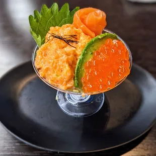 a small glass of food on a black plate