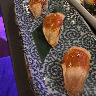 three pieces of sushi on a blue and white plate