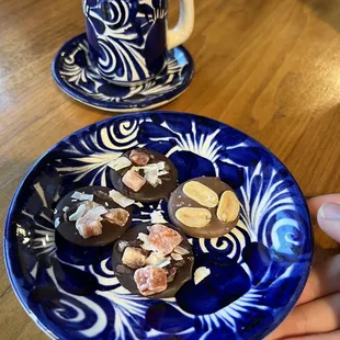 a hand holding a plate of chocolates