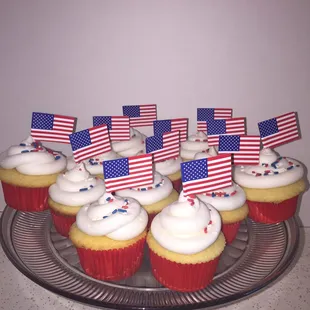 Vanilla Cupcakes with buttercream and some sprinkles topped with an American Flag.