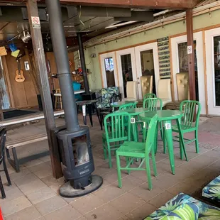 a patio with green chairs and a wood stove