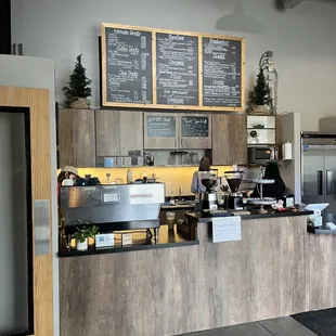 a coffee shop counter with a menu on the wall