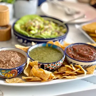 a plate of chips, salsa, and salsa dips