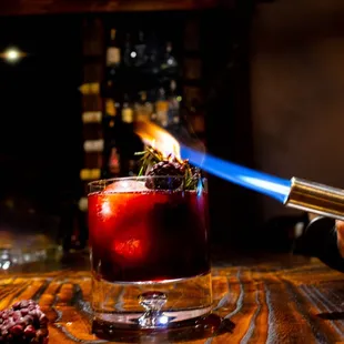 a person using a lighter to light a cocktail