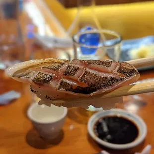 a person holding a piece of food with chopsticks