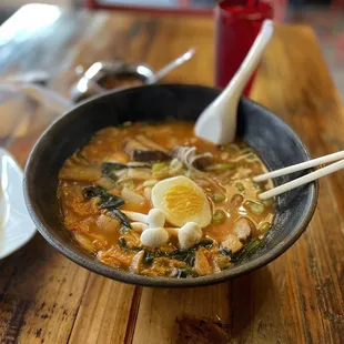 a bowl of ramen with chopsticks on a wooden table