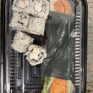a plastic container of sushi