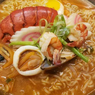 a close up of a bowl of ramen with a lobster