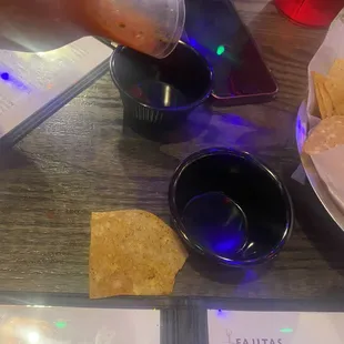 a person dipping sauce into a bowl of chips