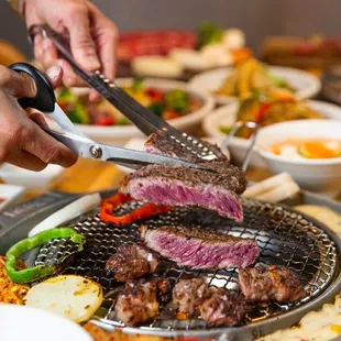 a person cutting a steak on a grill