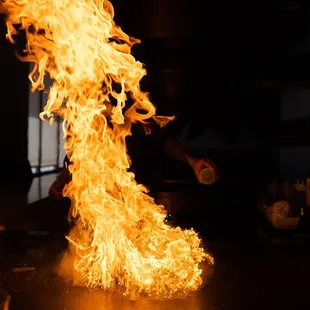a person cooking in a kitchen with flames