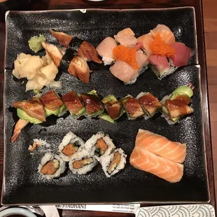 a plate of sushi with sauce and chopsticks