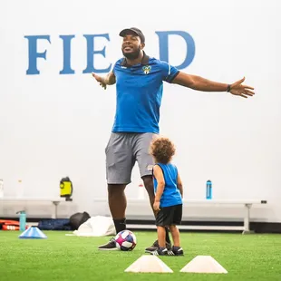 Coach running a practice while his son looks on.